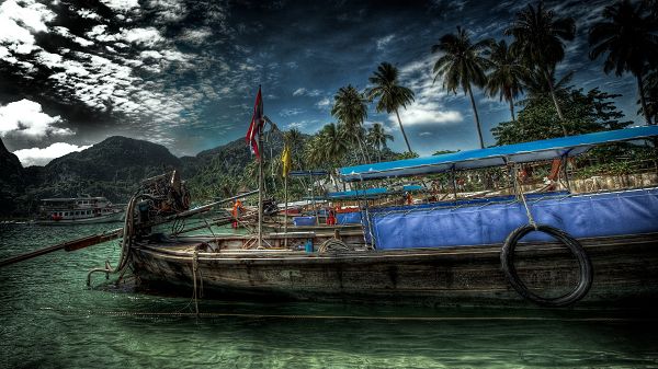 click to free download the wallpaper--Beautiful Beach Scene - Coconut Trees All Over the Beach, an Old Boat on the Clear River, the Dark Sky